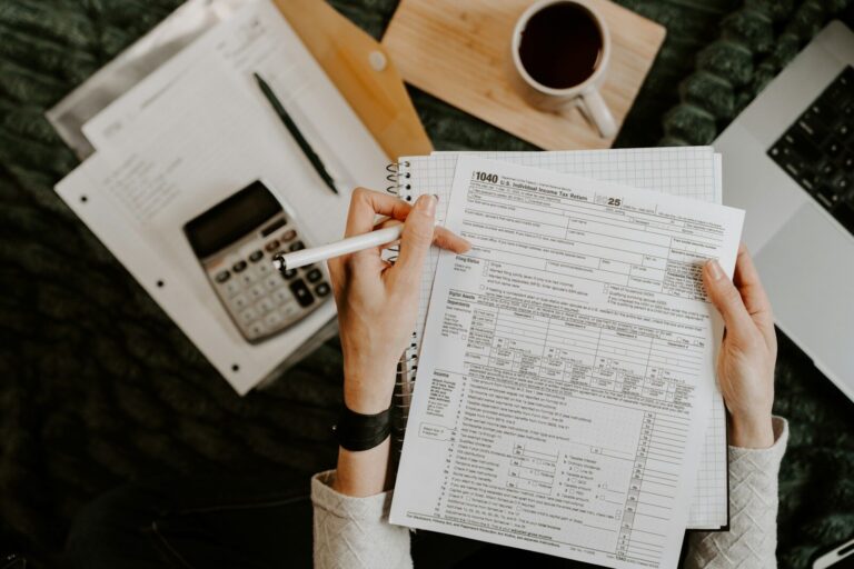 Person reviewing documents with calculator and laptop