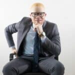 man in black suit jacket and black pants sitting on chair